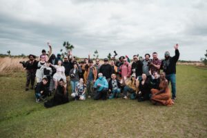 A diverse group of photographers posing together in a natural setting with cameras.