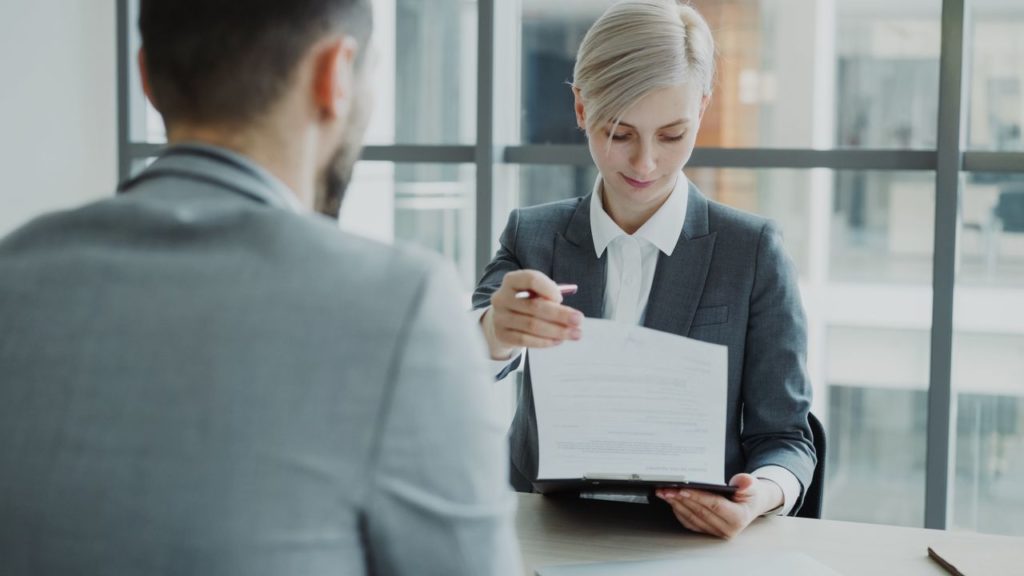 Business professionals reviewing a contract in a modern office setting.